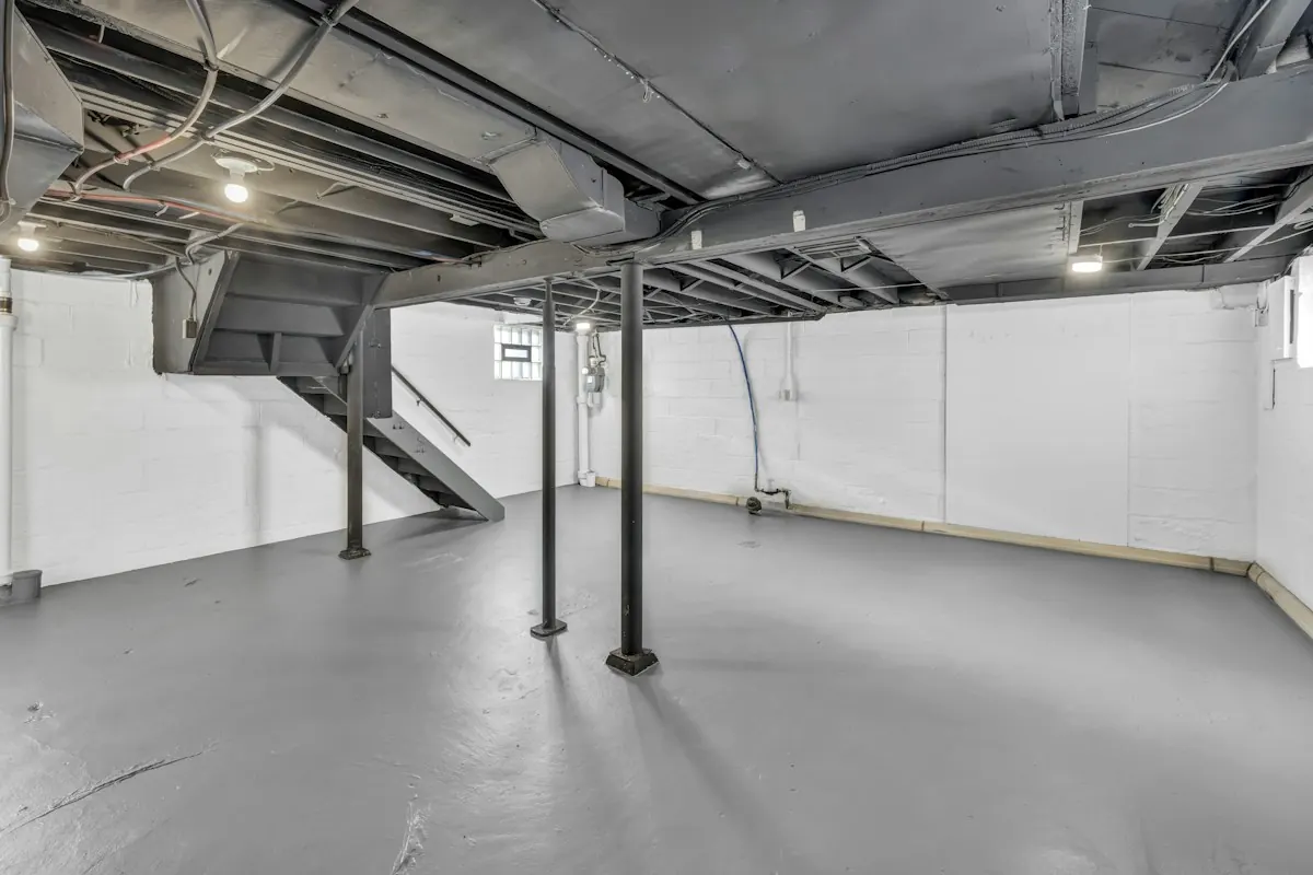 Unfinished basement with exposed ceiling joists and support posts