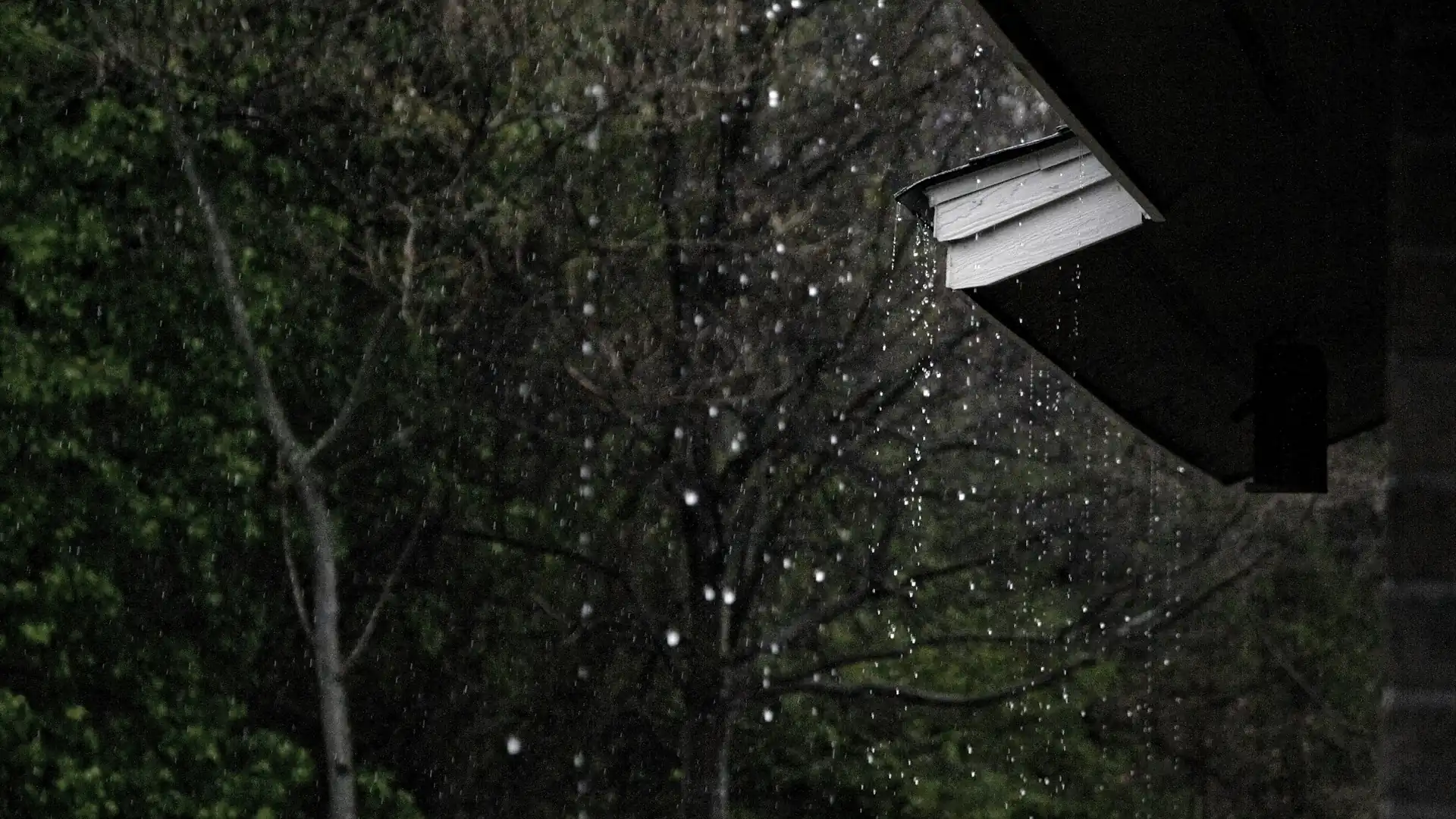 Rain pouring off a roof edge at dusk